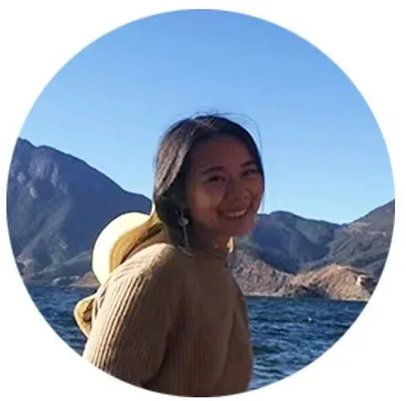 张亮亮的圆形头像照，她面带微笑，身穿棕色毛衣，背景是湖泊与山脉。