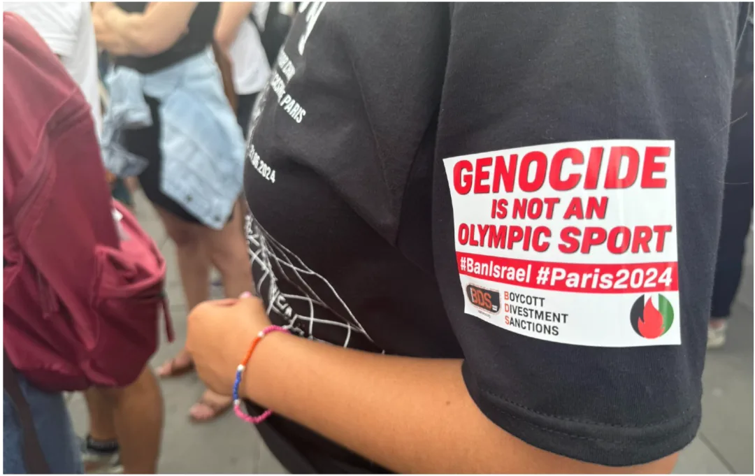 手臂上的贴纸写着“GENOCIDE IS NOT AN OLYMPIC SPORT #BanIsrael #Paris2024”,并附有“抵制、撤资、制裁”(BDS)标志。