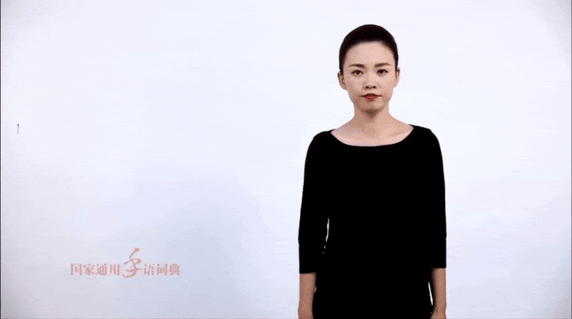 视频截图:一名女子站在白色背景前,双手自然垂放,画面左下角印有“国家通用手语词典”水印。