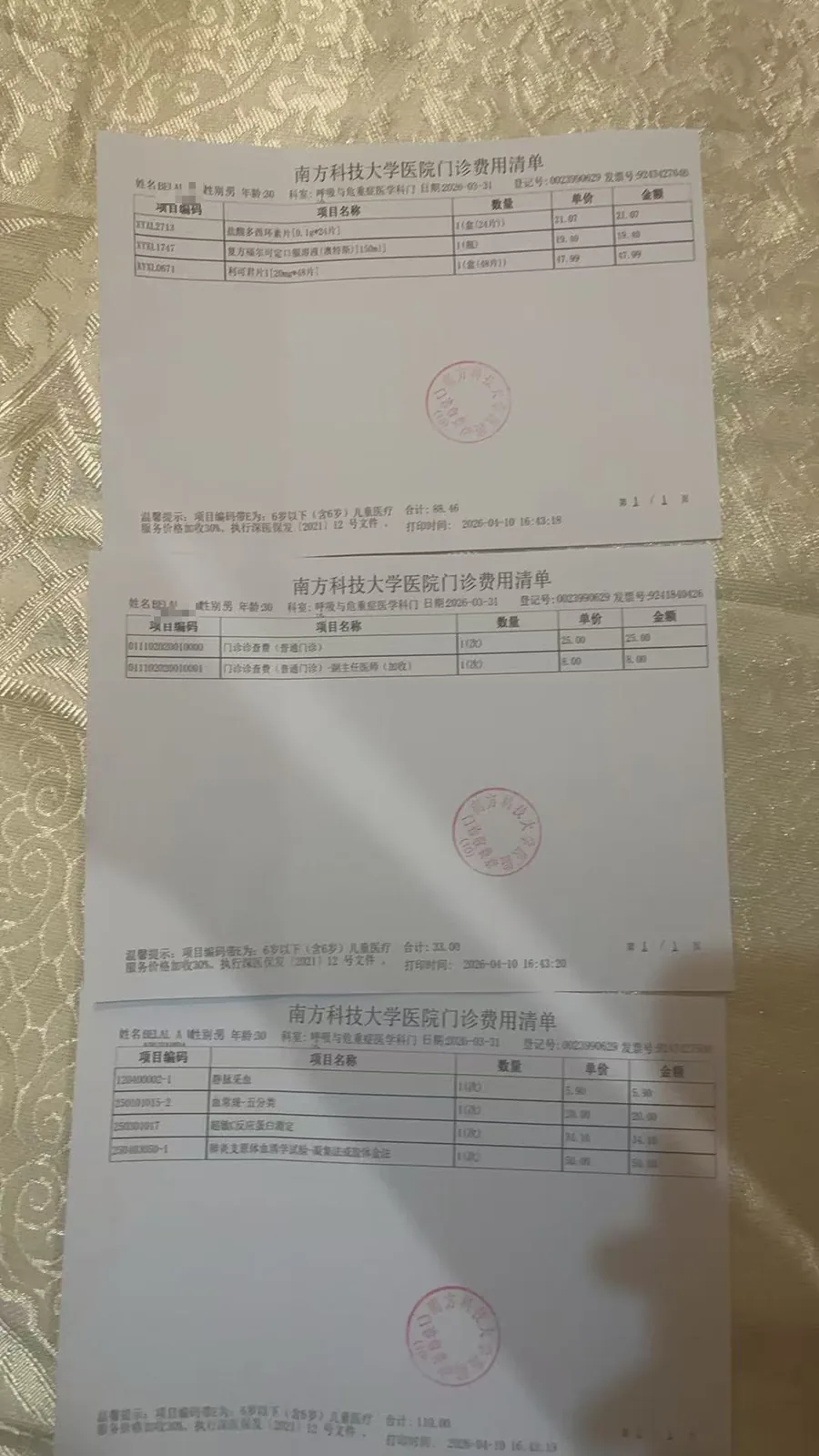 三张南方科技大学医院门诊费用清单叠放在织物上，分别列出药费、检查费等收费项目及金额，均盖有医院印章。
