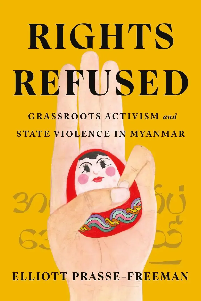 书封《Rights Refused: Grassroots Activism and State Violence in Myanmar》，作者 Elliott Prasse-Freeman；黄色背景上一只手掌张开，掌心画着一枚圆形人偶图案，人偶手中缠绕彩色绳结，背景隐约印有缅文字符。