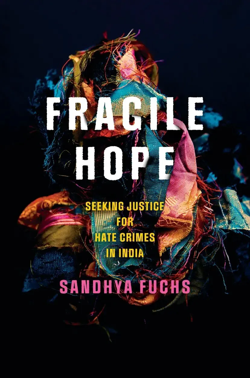 书封《Fragile Hope: Seeking Justice for Hate Crimes in India》，作者 Sandhya Fuchs；黑色背景中一团色彩斑斓、缠绕纠结的碎布与丝线。