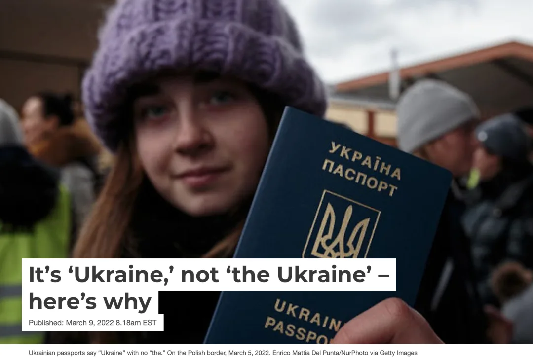 网页截图,标题为'It's 'Ukraine,' not 'the Ukraine' – here's why',配图是一名戴毛线帽的年轻女性在边境展示乌克兰护照,封面印有'УКРАЇНА ПАСПОРТ'字样和国徽。