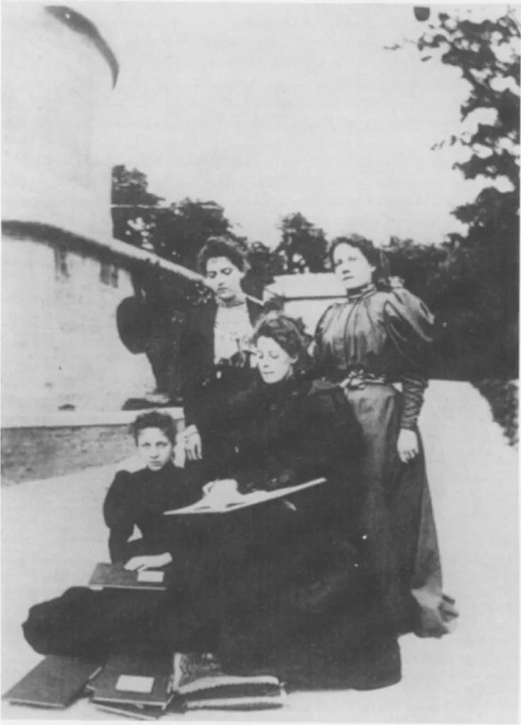 黑白老照片,四名身穿维多利亚时代深色长裙的女性在天文台建筑外合影,一人端坐膝上放着记录本,脚边堆着几本账簿。