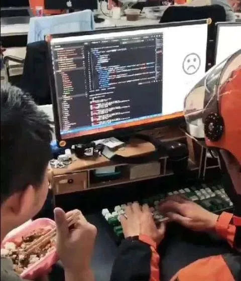 拼贴图片:左侧一人边吃盒饭边看电脑屏幕上的代码,屏幕角落有一个哭脸表情;右侧同一张桌子前坐着戴橙色头盔、穿橙色工作服的外卖骑手模样人物,正在敲键盘。