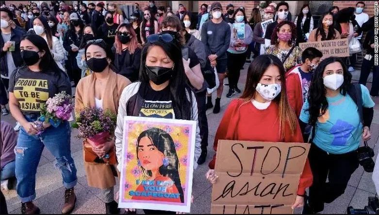 一群戴口罩的亚裔女性举著「STOP ASIAN HATE」和「我不是你的替罪羊」标语牌参加游行，有人手捧鲜花