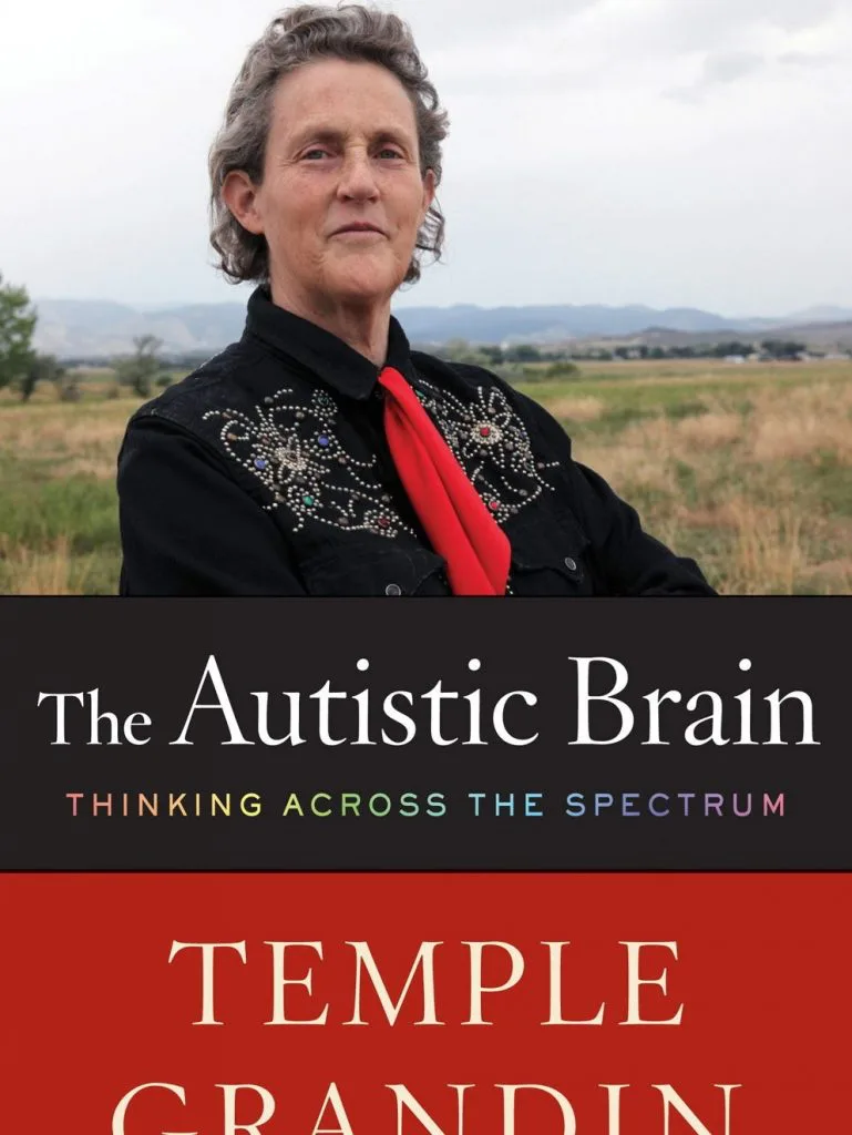 封面上方是Temple Grandin的照片,她身穿黑色绣花衬衫、系红色围巾,站在草原背景前;下方书名为《The Autistic Brain: Thinking Across the Spectrum》(自闭的大脑:跨越谱系的思考)。