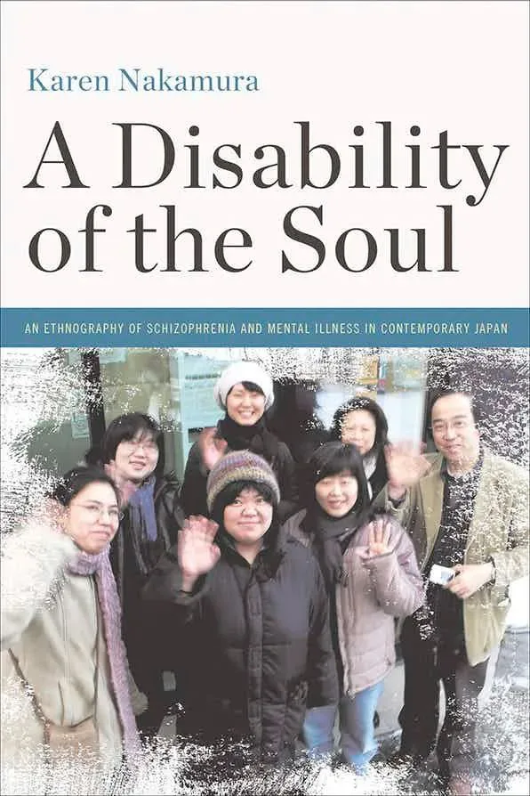 书影，《A Disability of the Soul: An Ethnography of Schizophrenia and Mental Illness in Contemporary Japan》书封，作者Karen Nakamura，下方是一张多人户外合影，几位社区成员微笑并挥手。