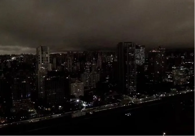 圣保罗城市天际线在浓烟笼罩下几近全暗,高楼与街道的灯光在昏暗天色中隐约闪烁,呈现白昼如夜的景象。