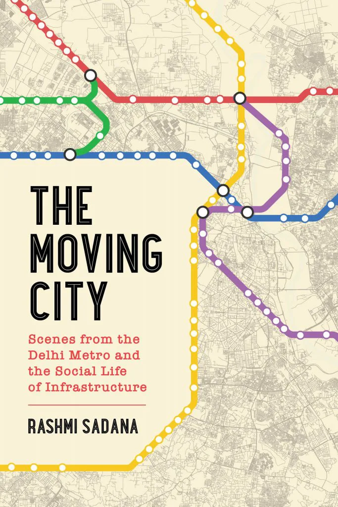 《行驶中的城市》（The Moving City: Scenes from the Delhi Metro and the Social Life of Infrastructure）封面，作者拉什米·萨达娜（Rashmi Sadana）。以城市地图为底纹，叠加彩色的德里地铁线路示意图，红、绿、蓝、黄、紫多条线路交织。