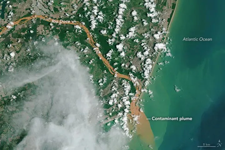 卫星图像显示多西河呈浑浊橙红色,携带泥沙流入大西洋,入海口处形成明显污染羽流,图中标注了河流、海洋与污染羽流位置。