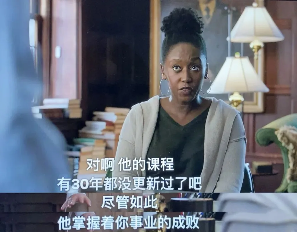 美剧《英文系主任》剧照：一位黑人女性在满是书籍的办公室里说话，字幕写着“对啊，他的课程有30年都没更新过了吧，尽管如此他掌握着你事业的成败”。