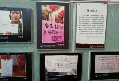 展墙陈列多幅图文，一张海报大字写着“合法讨薪流程”，一张说明牌题为“维权成本”，另有工人举牌讨薪的黑白照片，具体说明文字模糊难辨。