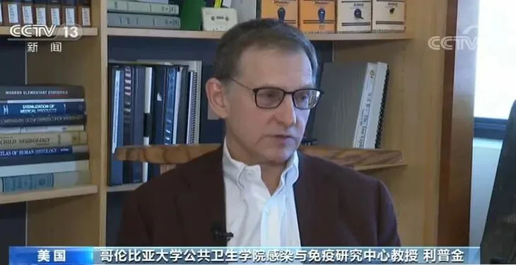 央视新闻画面,字幕显示“美国 哥伦比亚大学公共卫生学院感染与免疫研究中心教授 利普金”,一位戴眼镜、穿栗色外套的男性正接受采访,身后是书架。