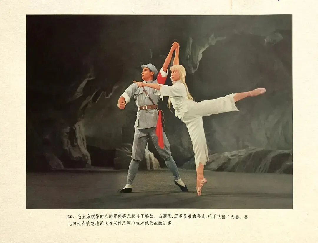 彩色剧照，男舞者身着灰色军装伸手指向前方，女舞者身着白色芭蕾服单腿立起、双臂上举，背景是山洞布景；图片下方印有说明文字，讲述喜儿向大春控诉恶霸迫害的情节。
