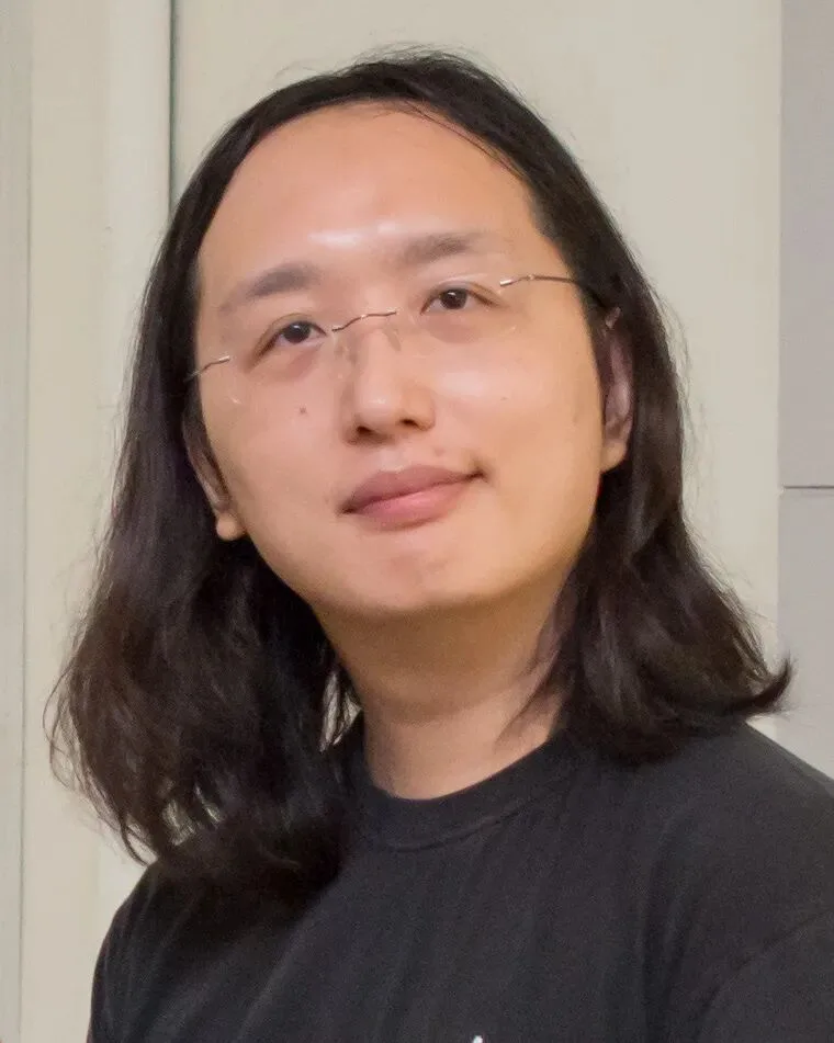唐凤的正面肖像照,长发披肩,戴细框眼镜,穿深色T恤,微笑面对镜头。