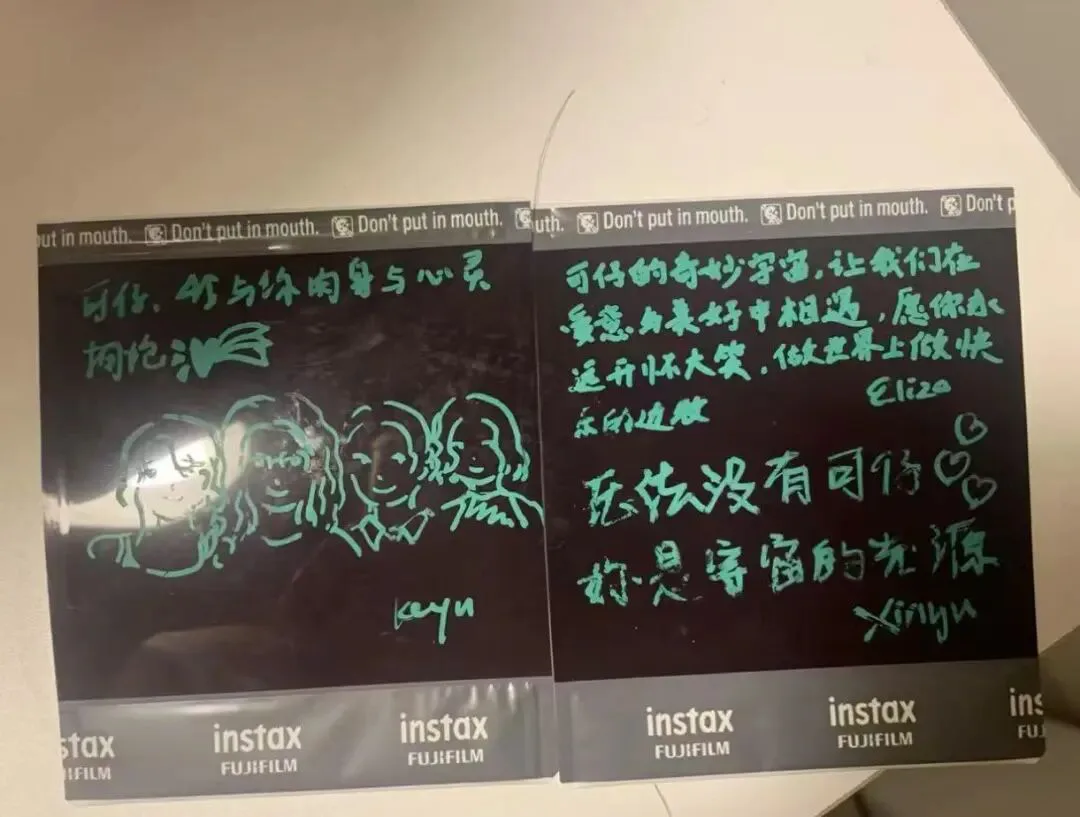 两张黑色即影即有照片，用荧光绿笔书写；左边画着四张卡通脸孔并签名“keyu”，右边写满祝福留言，落款可见“Eliza”与“xinyu”字样。